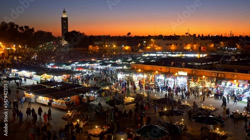 Crowds of people coming and going on Jemaa el-Fnaa marketplace of Marrakesh, Morocco just after sunset. Many counters with various goods. UHD photo