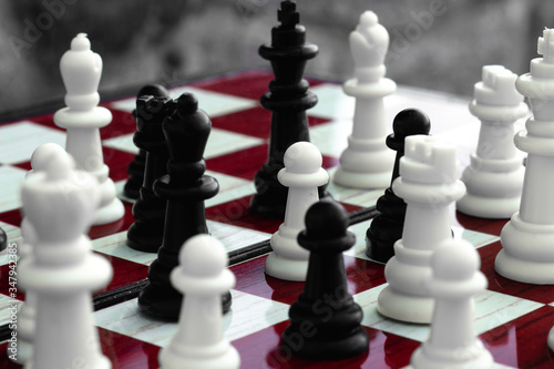 White and black chess in a chaotic arrangement  on a red-white chessboard on a stone background