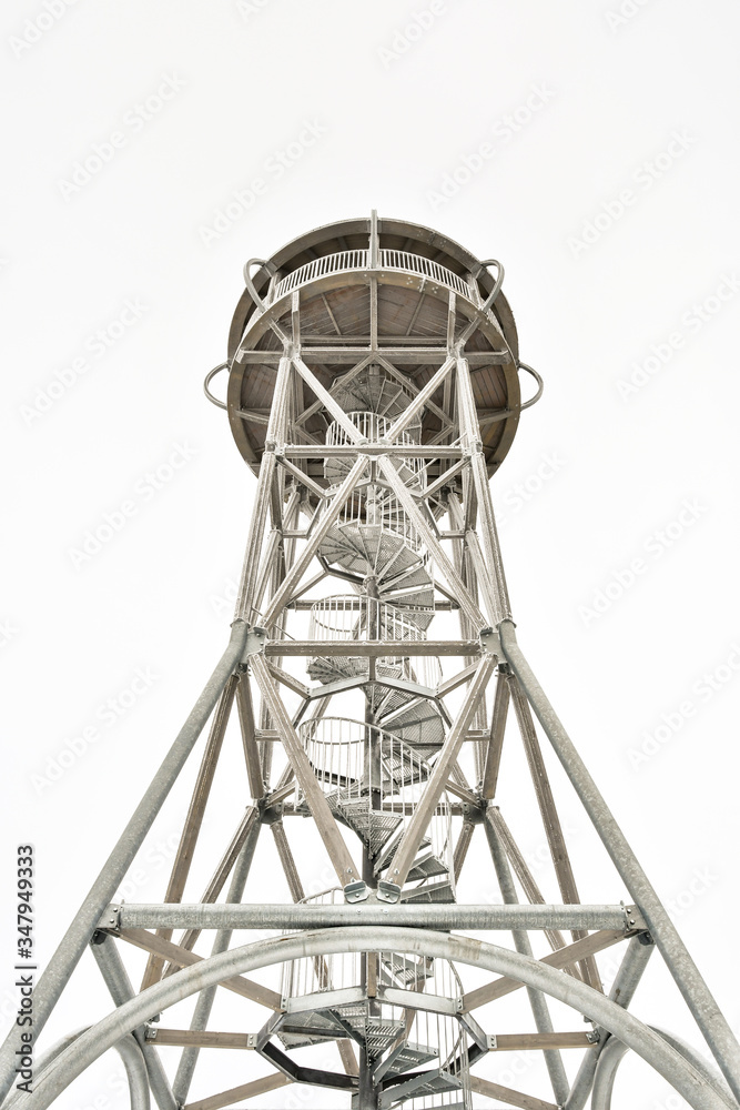 A winding metal staircase leading to the top of a frosted, high observation tower in the mountains A winding metal staircase leading to the top of a frosted, high observation tower in the mountains