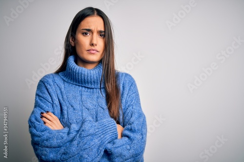 Young beautiful brunette woman wearing casual turtleneck sweater over white background skeptic and nervous, disapproving expression on face with crossed arms. Negative person. © Krakenimages.com