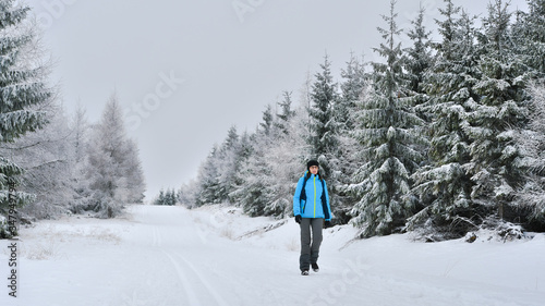 A young woman walks on the snow along a tourist trail.