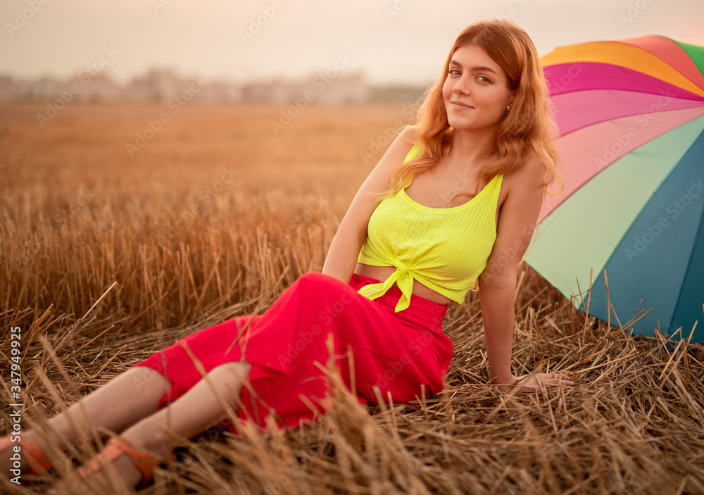 Relaxed woman sitting on dry grass near umbrella Relaxed woman sitting on dry grass near umbrella