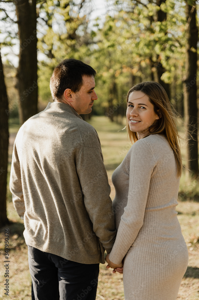 happy young pregnant couple walks in the park,husband holds the hand of his pregnant wife,future dad and mom,walks in the park after quarantine happy young pregnant couple walks in the park,husband holds the hand of his pregnant wife,future dad and mom,walks in the park after quarantine