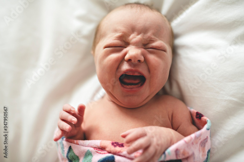 A cute Newborn baby crying in bed