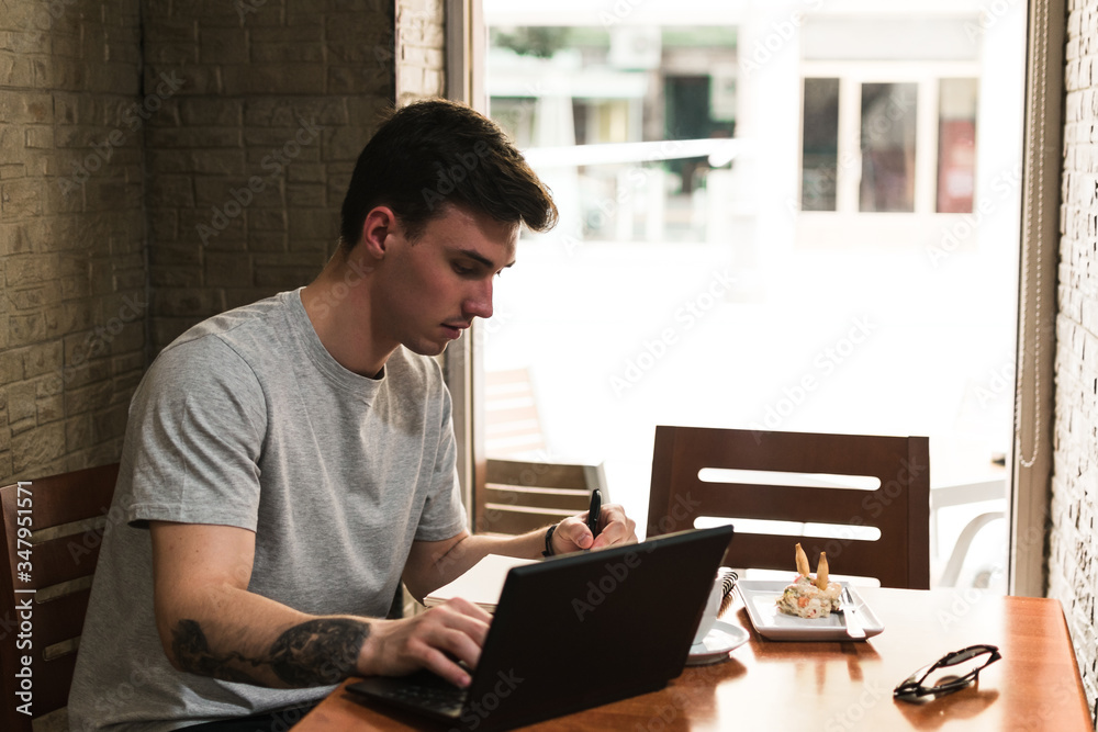 Freelancer sitting at cafe table and browsing laptop Freelancer sitting at cafe table and browsing laptop