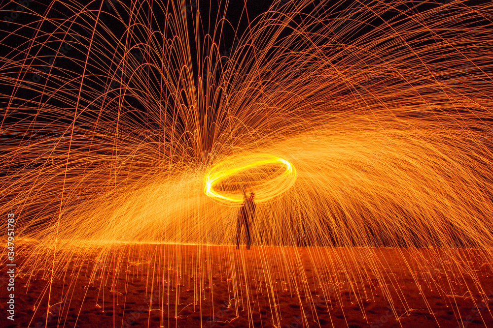 © Edgar Ortiz/ADDICTIVE STOCK - Long exposure silhouette of unrecognizable person spinning burning stick emitting sparkles while dancing with fire at night