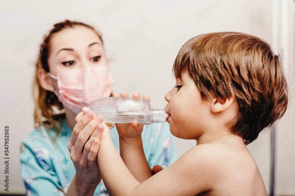 Little kid using inhaler in clinic during check up Little kid using inhaler in clinic during check up