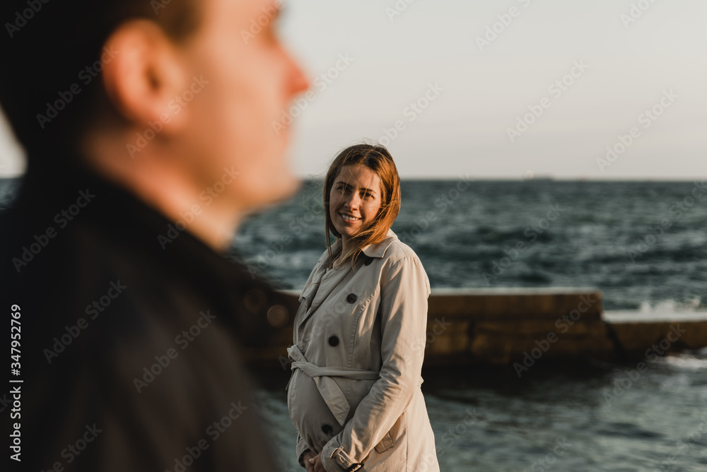 Young pregnant couple in love on summer sunny evening. at sunset on the beach,Beautiful young couple expecting a baby. A happy family. Pregnant mother and best father