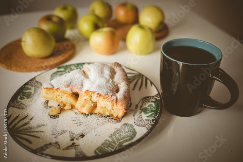 Apple pie on a plate with a green pattern. A cup of tea. A cup of coffee. Apples on the table. Green apples. A feast of apples. Tea party Tasty food. White background.
