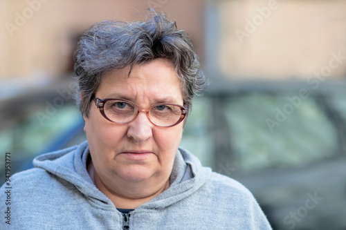 Portrait of an angry elderly adult woman looking at camera. Senior mature female senior citizen displeased, sad outside. Unhappy retirement concept. photo
