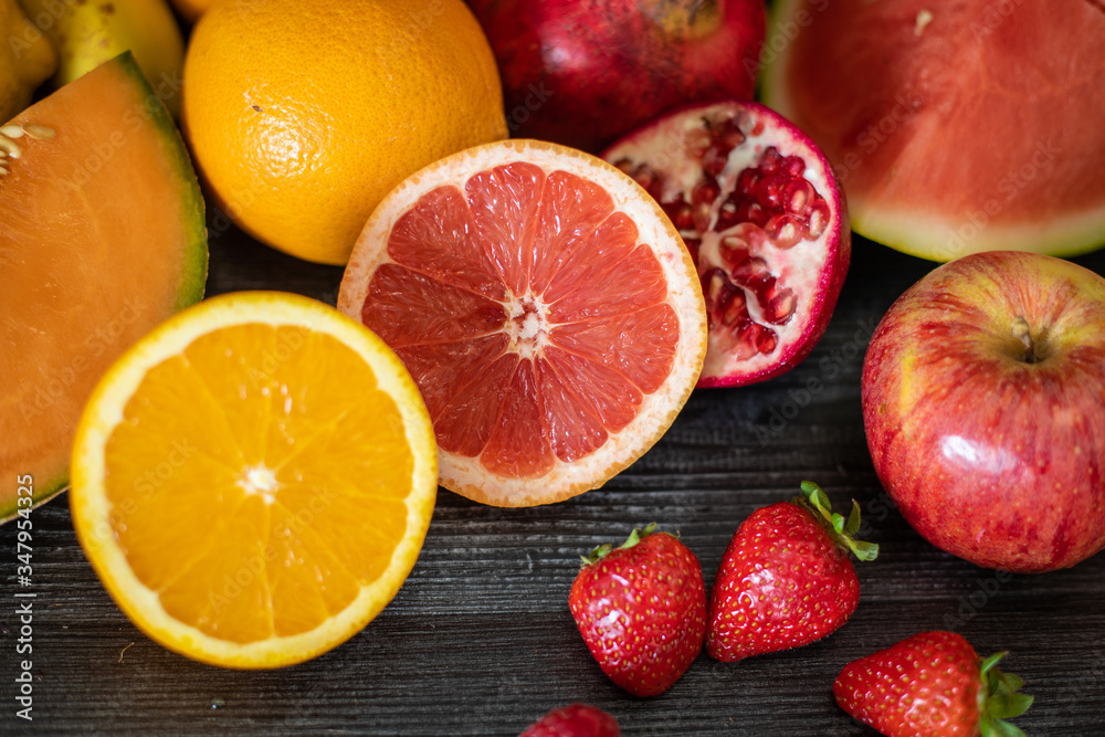 From above bunch of various fresh fruits full of vitamins placed on black lumber table From above bunch of various fresh fruits full of vitamins placed on black lumber table