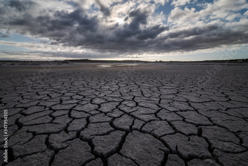 From above of drought cracked lifeless ground under colorful cloudy sky photo