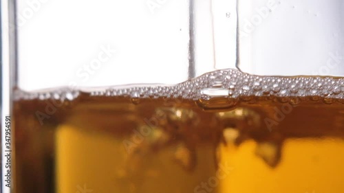 Apple juice pours into a glass, macro shooting slow motion