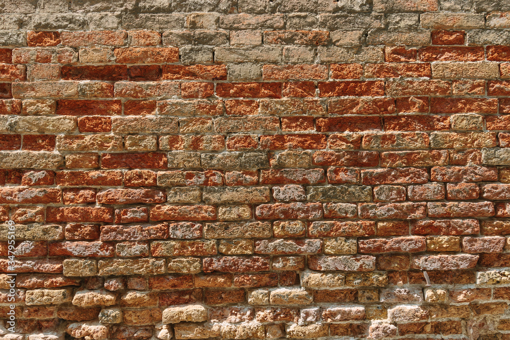 Obraz premium Stary tekstura ściany z cegły. Zwietrzała powierzchnia ściany. Grungy pomarańczowy mur. Tło czerwone stonewall. Odrapana fasada budynku w słoneczny dzień. Stary brązowy kamienny mur w mieście. Tło z cegły wiersza.