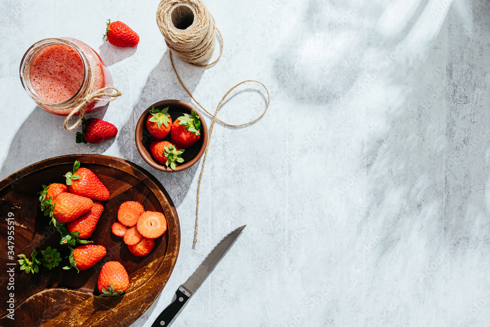 From above composition with fresh homemade strawberry juice in glass jar wrapped with twine placed on marble surface with whole berries and knife From above composition with fresh homemade strawberry juice in glass jar wrapped with twine placed on marble surface with whole berries and knife