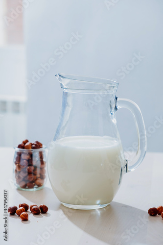 Jar of milk and hazelnuts on table photo