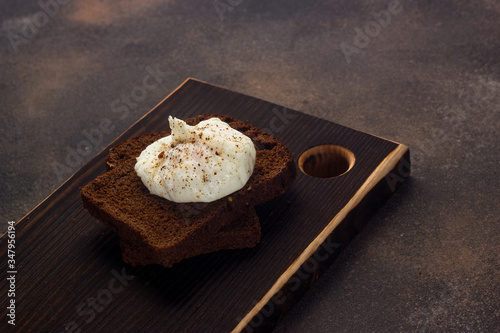 Healthy breakfast of toast with poached egg on a dark background