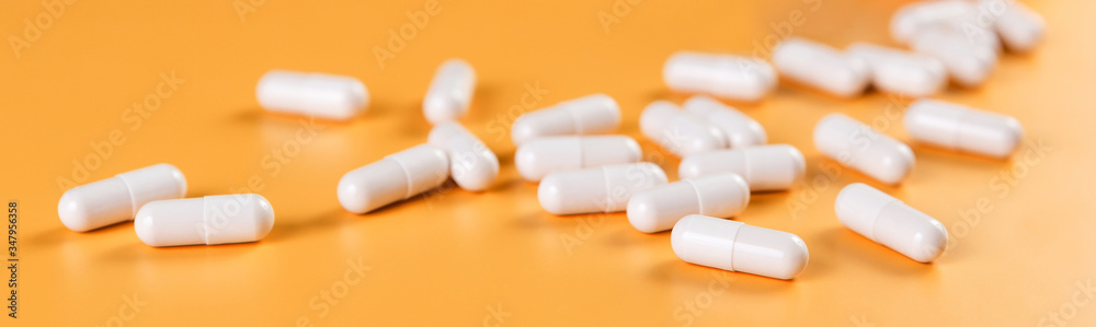 Pharmaceutical medicine white pills, tablets or capsules on yellow background. Pharmaceutical medicine white pills, tablets or capsules on yellow background.