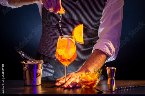 Bartender sprinkling Aperol spritz cocktail glass with orange juice