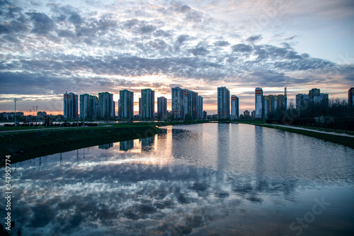 Stunning sunset view with beautiful sky above the high-rise buildings and reflection in the lake. Residential complex Sofia St. Petersburg.