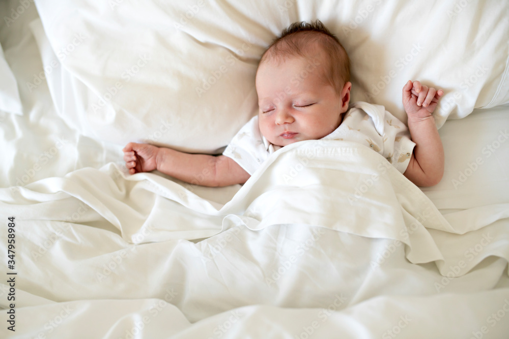 A Sweet newborn baby girl sleeping in white bed A Sweet newborn baby girl sleeping in white bed