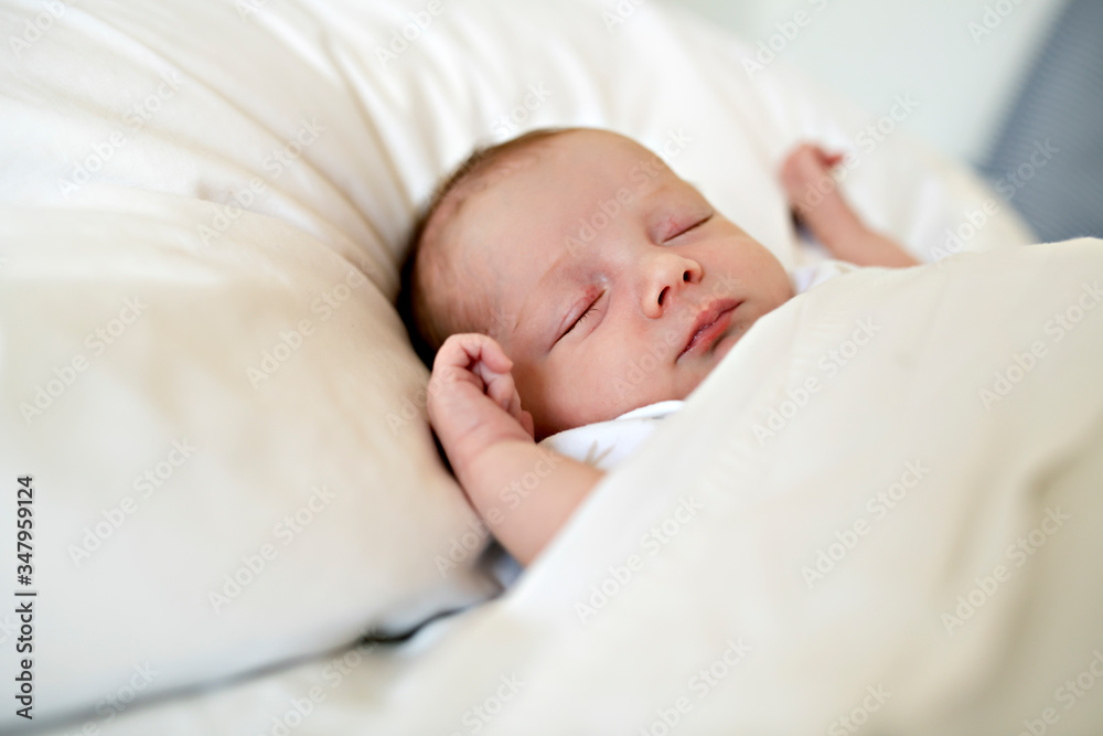 A Sweet newborn baby girl sleeping in white bed A Sweet newborn baby girl sleeping in white bed