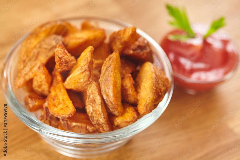 Fresh homemade crispy fried potato wedges in glass bowl with ketchup. Close up Fresh homemade crispy fried potato wedges in glass bowl with ketchup. Close up