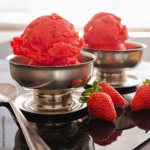Strawberry sorbet in a  individual stainless container. Natural fruits beside.