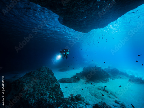 Seascape of coral reef in the Caribbean Sea / Curacao with Diver in cave "Blue Room"