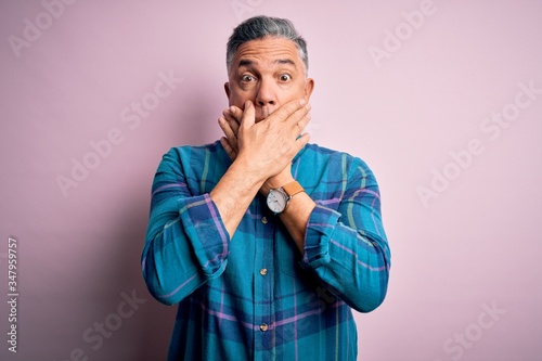 Middle age handsome grey-haired man wearing casual shirt over isolated pink background shocked covering mouth with hands for mistake. Secret concept.