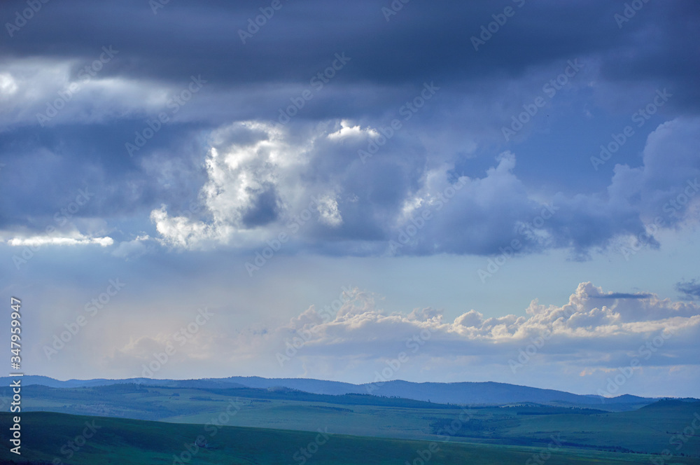 Rain clouds over distant hills at sunset. Zabaykalsky Krai. Russia.