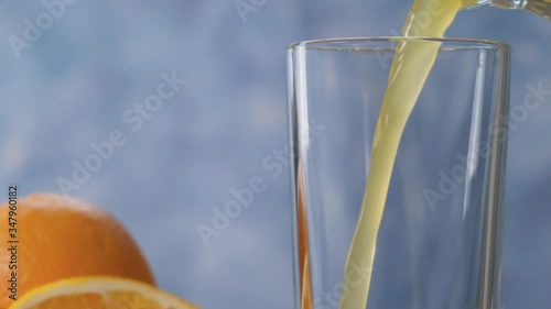Orange juice is poured into a transparent glass with a slow motion close-up