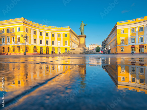 Odessa Ukraine -05-06-2020  golden lights and reflections in blue water under sky of buildings and monument of city founder Duke in Odessa in Ukraine with copy space