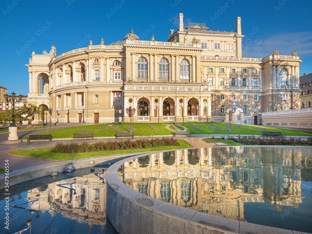 view through fountain to facade of opera theater in Odessa with reflections in water in the morning with copy space