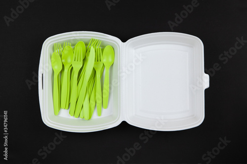 Photos Biodegradable reusable recyclable green forks, spoons, knifes made from corn starch in white container on black background