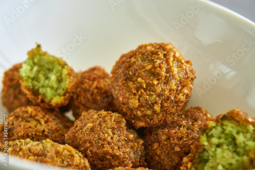 Close-up of fresh and crispy falafels balls inside a white bowl, authentic deep fried chickpea hot round falafels
