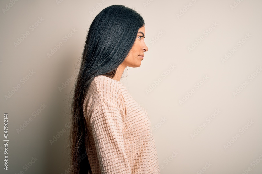 Young beautiful hispanic woman wearing elegant pink sweater over isolated background looking to side, relax profile pose with natural face with confident smile. Young beautiful hispanic woman wearing elegant pink sweater over isolated background looking to side, relax profile pose with natural face with confident smile.