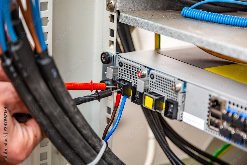 Using a multimeter. Rack of equipment, wires. Wiring. Only hands. Horizontal orientation. Using a multimeter. Rack of equipment, wires. Wiring. Only hands. Horizontal orientation.