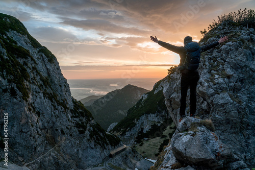 A man stands on the rock at sunrise in the Alps