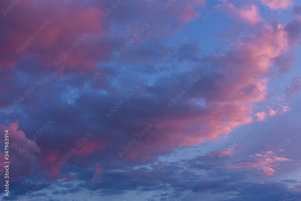 Cloudy sunset sky. Lilac light on a blue cloudy sky.