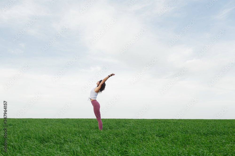 Young slim girl doing yoga outdoors in a green field Young slim girl doing yoga outdoors in a green field
