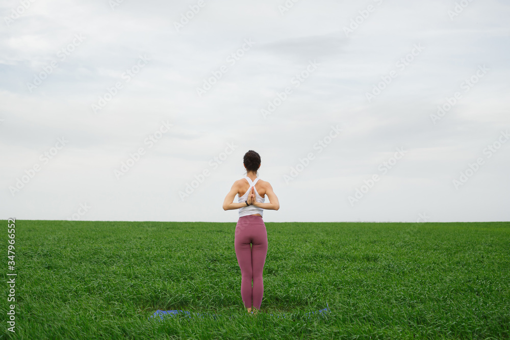 Young slim girl doing yoga outdoors in a green field Young slim girl doing yoga outdoors in a green field