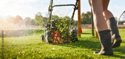 Foto Lawn mover on green grass in modern garden.