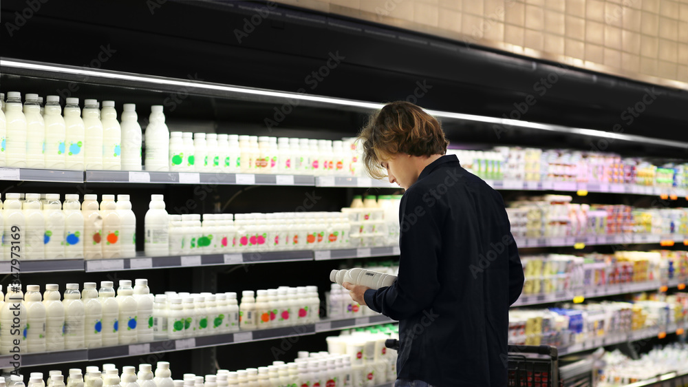 Teenager shopping in supermarket, reading product information	