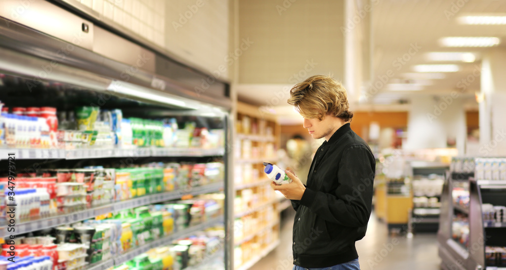 Young man shopping in supermarket, reading product information	