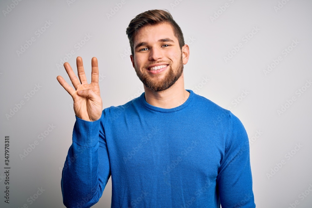 Young handsome blond man with beard and blue eyes wearing casual sweater showing and pointing up with fingers number four while smiling confident and happy.