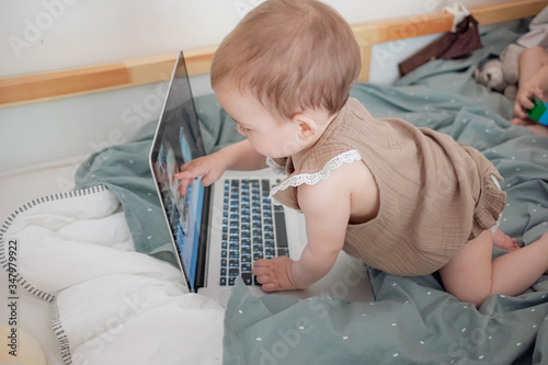 Little infant girl video chatting with family, infant baby with laptop on neutral colours background