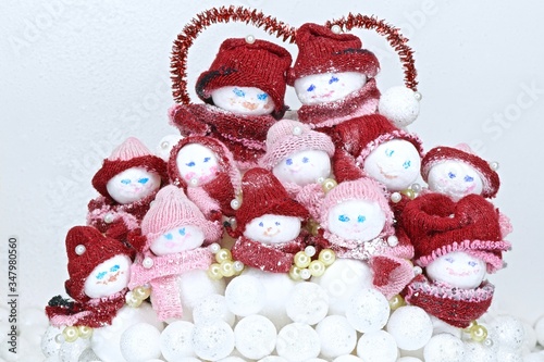 family of toy snowmen in red hats and scarves