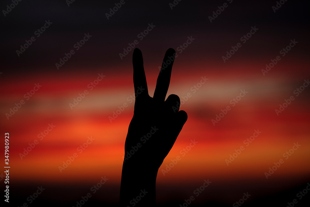 Freedom sign silhouette and sunset background.