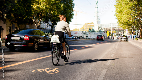 Cycle lane with orange painted bike on asphalt. Bicycle lane and car traffic. Ecological green urban transport. Fahrradspur und Autoverkehr. Fahrrad Zeichen auf Straße. Ökologischer urbaner Verkehr.